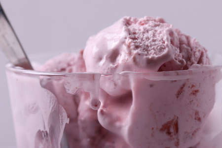 tasty cold melting strawberry and raspberry icecream in a glass container. close up shot.