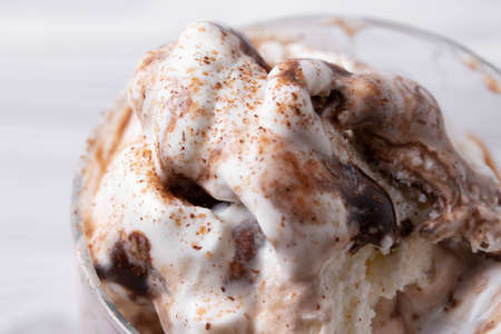 delicious creamy milky vanilla ice cream with caramel and chocolate addings in a glass container on...