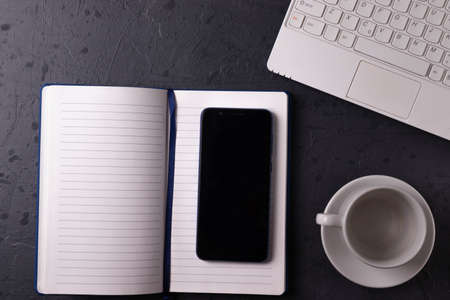 a white laptop and open notebook on the grunge stone concrete surfaceの写真素材