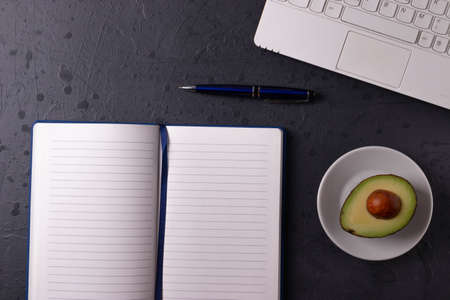 a white laptop and open notebook on the grunge stone concrete surface
