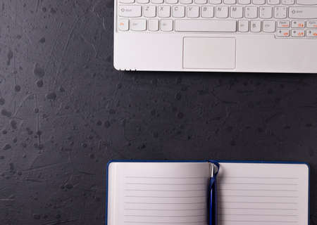 a white laptop and open notebook on the grunge stone concrete surface