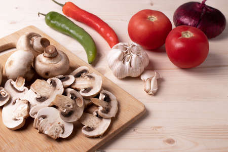 raw champignon mushrooms and tomatoes and chilli papers on the rustic wooden surface