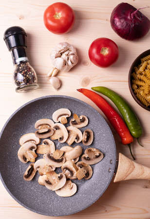 raw champignon mushrooms and tomatoes and chilli papers on the rustic wooden surfaceの写真素材
