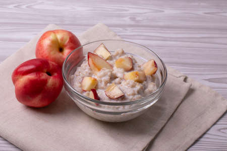 morning oat meal in a glass bowl with peachesの写真素材