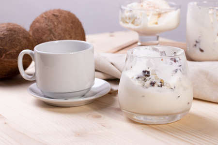 delicious creamy milky vanilla ice cream with caramel and chocolate addings in a glass container on the light rustic backgroundの写真素材