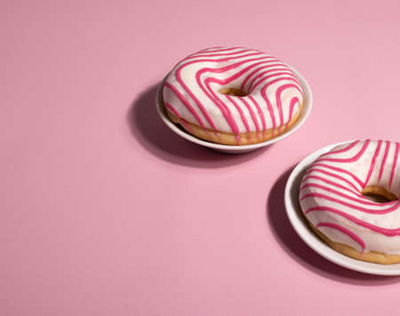 yummy sweet pink and white striped icing doughnutの写真素材