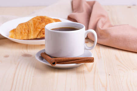 a white ceramic cup with black espresso, french croissant as breakfast or snack concept on rustic, natural texture wooden surfaceの写真素材