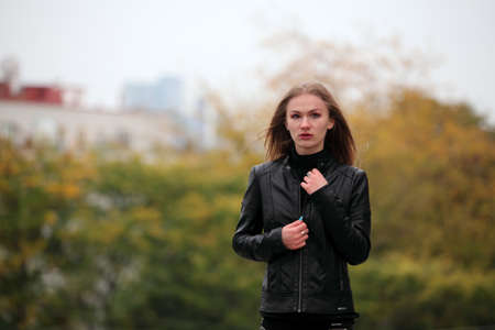 Beautiful blonde girl in black leather jacket in autumnの写真素材