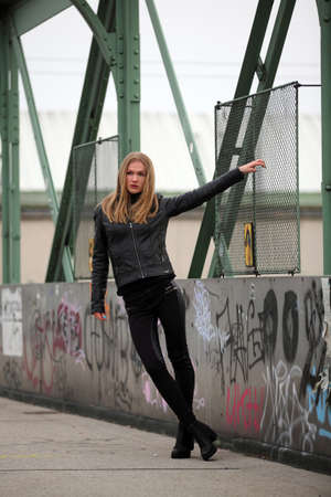Beautiful blonde girl in black leather jacket and leggingsの写真素材