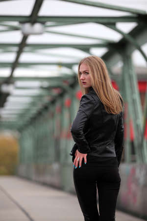 Beautiful blonde girl in black leather jacket and leggingsの写真素材