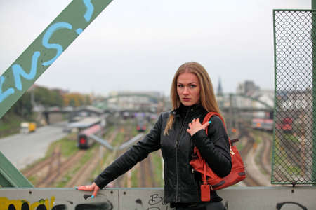 Beautiful blonde girl in black leather jacket in front of Railroad Tracksの写真素材