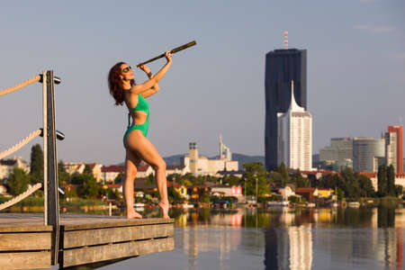 Woman in green swimsuit looking through a monocularの写真素材