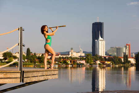 Woman in green swimsuit looking through a monocularの写真素材