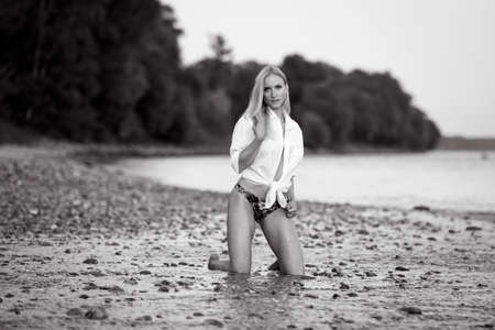 Athletic bikini girl kneeling at a riverの写真素材