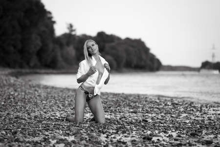 Athletic bikini girl kneeling at a riverの写真素材