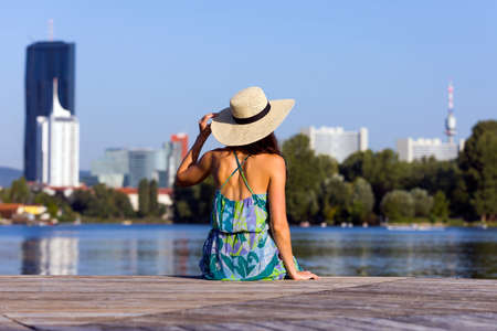Back portrait of a young woman wearing dress and hatの写真素材