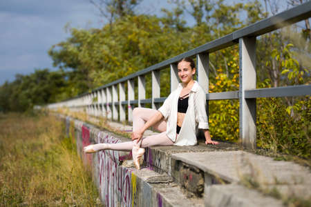 Young Ballerina sitting at a handrail outdoorの写真素材