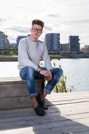 Handsome young man wearing jeans, sweater and glassesの写真素材