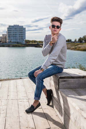 Handsome young man wearing jeans, sweater and sunglassesの写真素材