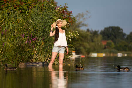 Attractive young woman with long brunette hair in a lakeの写真素材