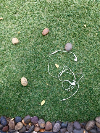 Earphone on background of grass and stoneの写真素材