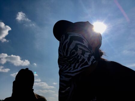 Black people cover face on sky sunshine backgroundの写真素材