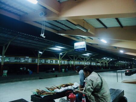 Woman seller to sale grilled chicken waiting passenger on morning train marketの写真素材