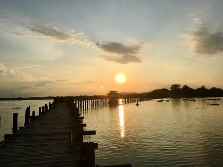 The U Bein Bridge is old longest wooden bridge in Mandalay city, Myanmar on sunset scene twilight sky backgroundの写真素材