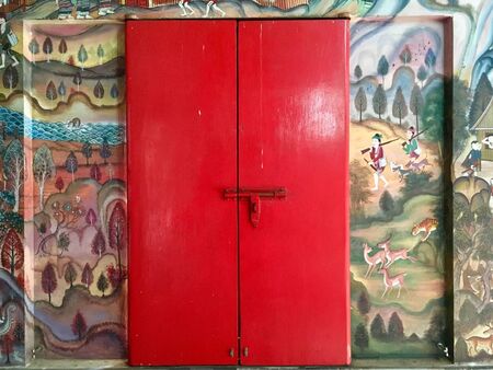 Old red door and mural wall painting ancient style interior of North Thai templeのeditorial素材