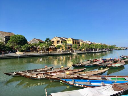 Scenery view of mustard yellow building style and traditional boat on river at Hoi An ancient town, Vietnamのeditorial素材