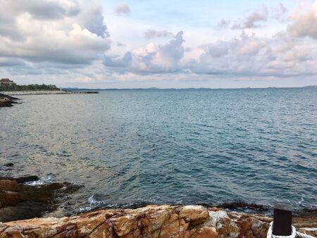 Scenery of empty sea beach with reef coast foreground and blue sky on summerの写真素材