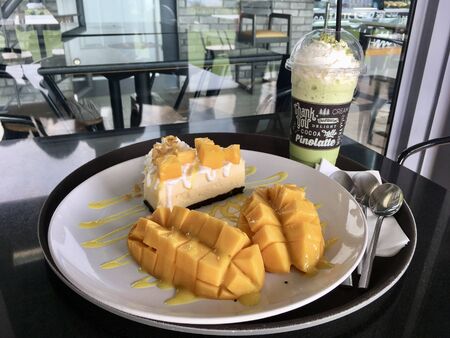 Mango cheesecake with fresh mango and matcha frappe drink, enjoy dessert order in CafÃ©の写真素材