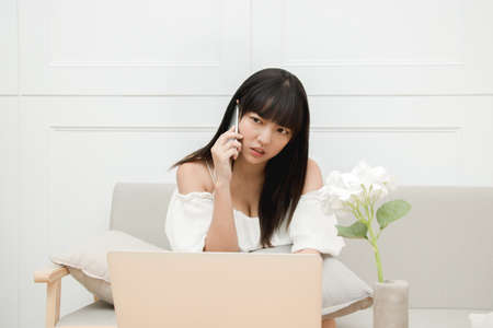 Frustrated annoyed woman confused by computer problem and talking on phone.の写真素材