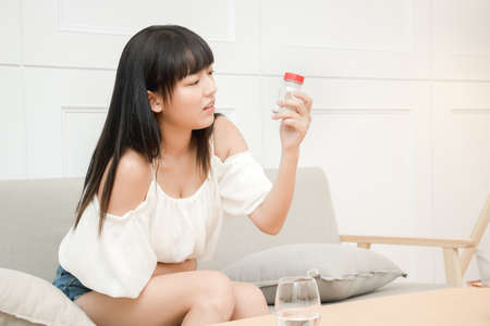 Young female suffering form abdominal pain. Causes of abdominal pain include dysmenorrhea, endometriosis, PMS, ovarian cyst or Gastroenteritis. Gynecology and health care concept.の写真素材