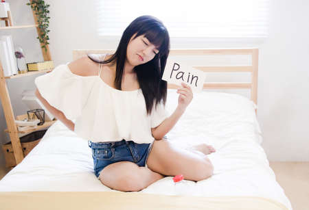Beautiful young woman suffering from backache at home.の写真素材