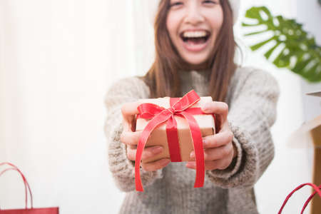 Smiling young woman deliver the Christmas present box.