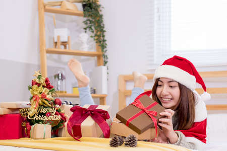 Smiling young woman with Christmas present box on the bed.の写真素材