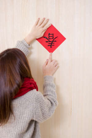 Beauty woman paste red envelope on the wall in chinese new year.の写真素材