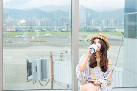 Relaxation and technology. Young asian woman drinks coffee and listens to the music by mobile phones.の写真素材