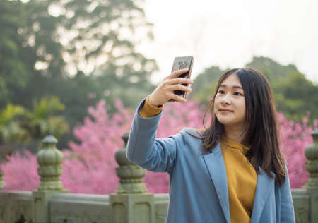 Tamsui Palace, Tamsui Town, New Taipei City-Feb 2,2019: Woman taking a Selfie with cherry blossom.のeditorial素材