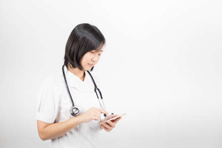 Young asian nurse with a stethoscope talking on the phone, isolated over white background.の写真素材