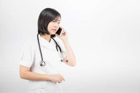 Young asian nurse with a stethoscope talking on the phone, isolated over white background.の写真素材