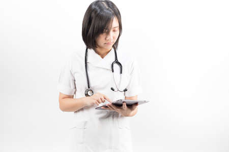 Young asian nurse with a stethoscope using a digital tablet, isolated over white background.の写真素材