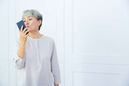 Senior Asia woman is working from home, using laptop and smart phone.