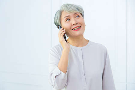 Senior Asia woman is working from home, using laptop and smart phone.の写真素材