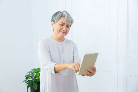 Senior Asia woman is working from home, using laptop and smart phone.の写真素材