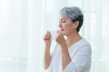 Asian senior woman suffer from cough with face mask protectionの写真素材