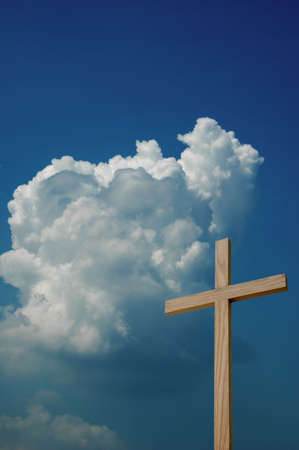 Wooden cross against sky with clouds