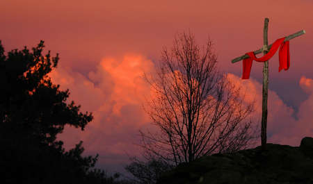 Cross with red linen on a sunset backgroundの写真素材