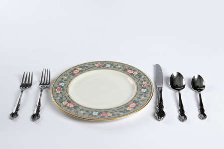 Plate set with silverware and fine Chine over a white background.